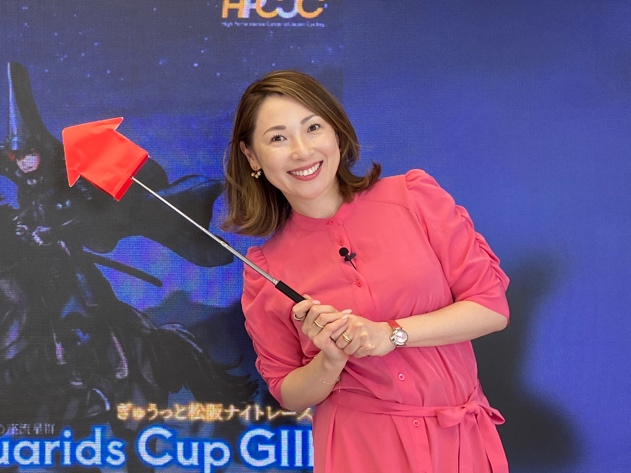 2026年、ピンクの衣装で赤旗を持つ津田三七子(松阪ナイトレース収録)