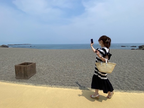 高知・桂浜の砂浜で海を背にスマートフォンを構える津田三七子